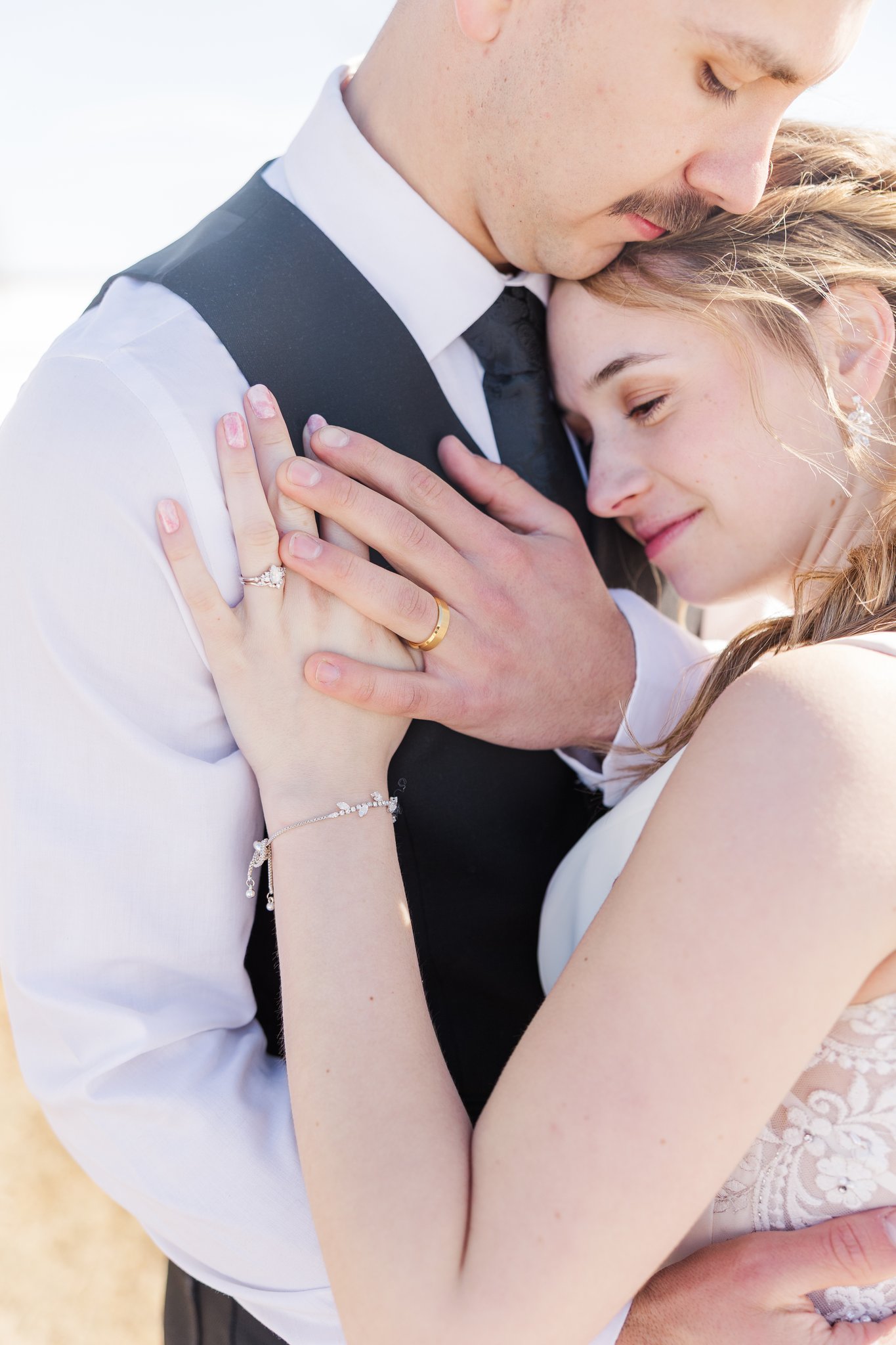 Bride sitting on vintage car hood, groom holding cowboy hat