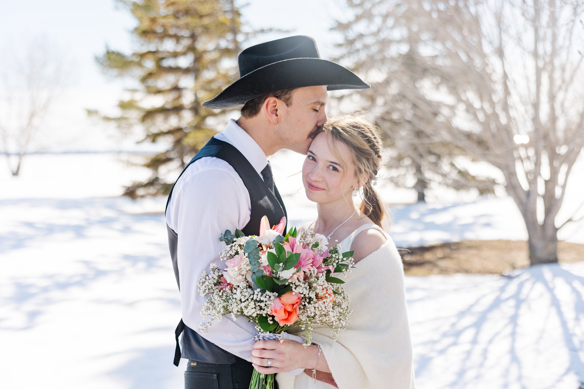 Bride and groom first look portrait in winter snow, groom in black cowboy hat