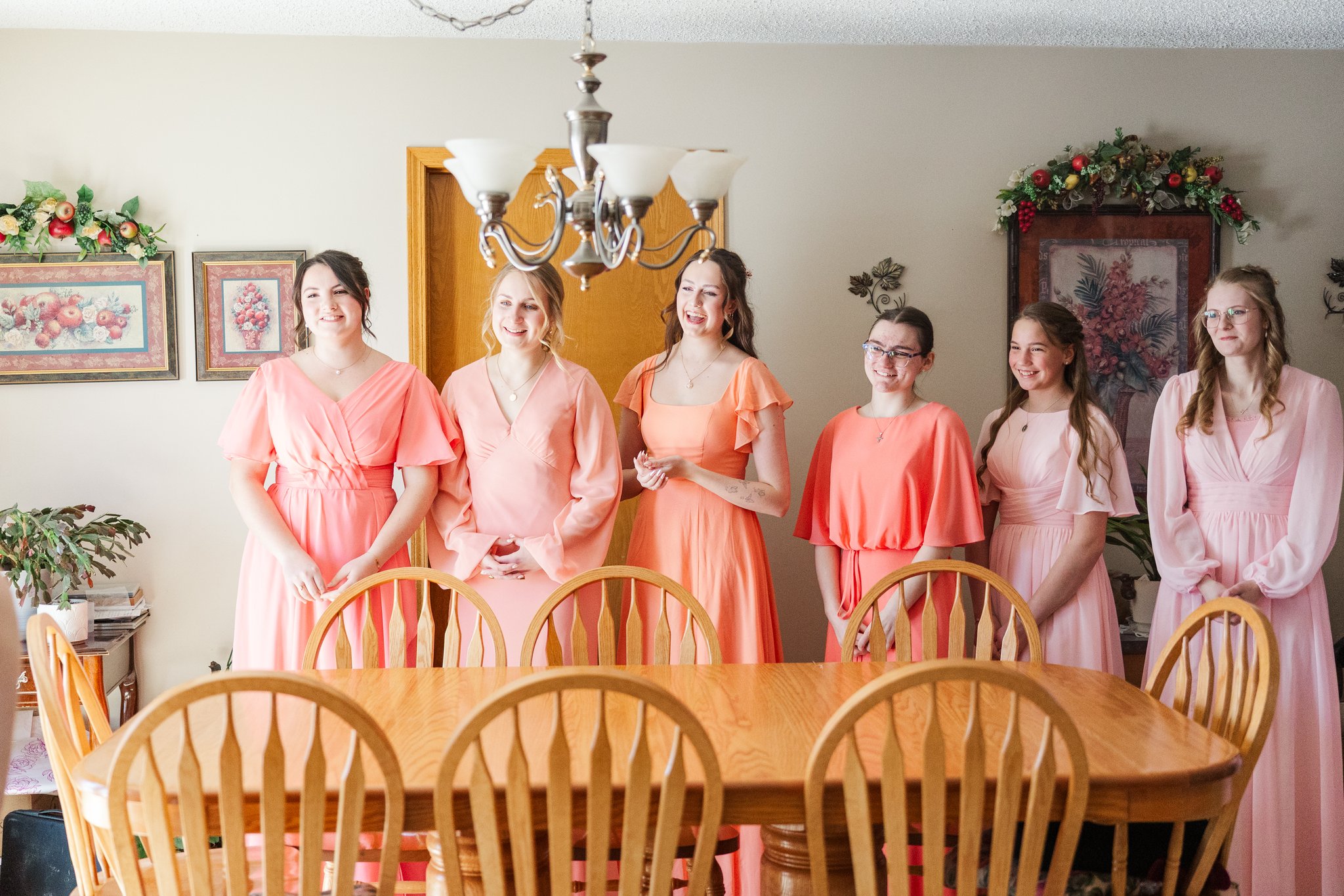 Bride with bridesmaids in coral dresses laughing together