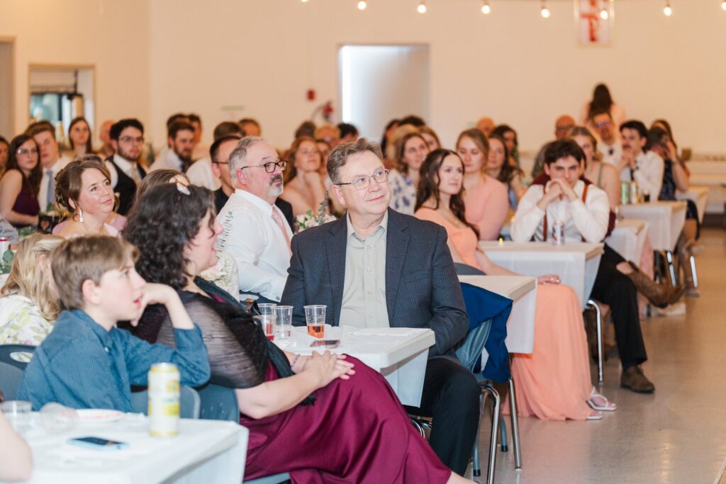 Black and white photo of wedding guests at reception during speeches
